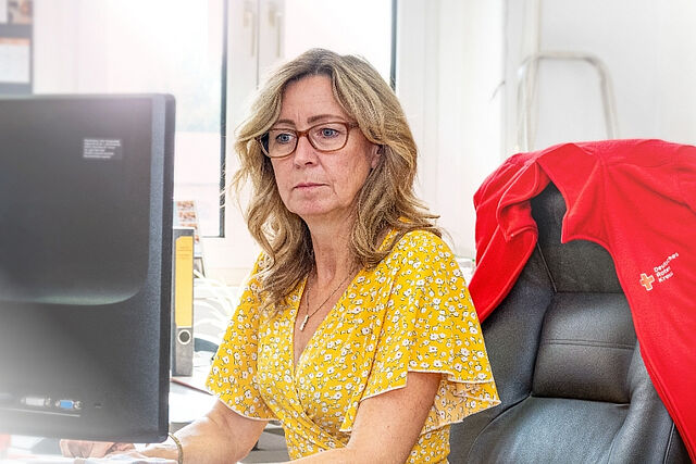 Ansprechpartner — DRK Regionalverband Magdeburg – Jerichower Land e. V. Janett Blut, Sekretariat des DRK Regionalverbands Magdeburg–Jerichower Land e. V., am Arbeitsplatz vor dem Computer.