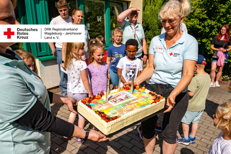 45 Jahre DRK-Kita „Rasselbande“ – Jubiläumstorte Kinder und Erzieherinnen halten eine große Jubiläumstorte mit der Aufschrift „45 Jahre Kita“.